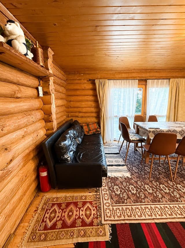 Всекидневна на първия етаж с диван и кът за хранене до прозореца